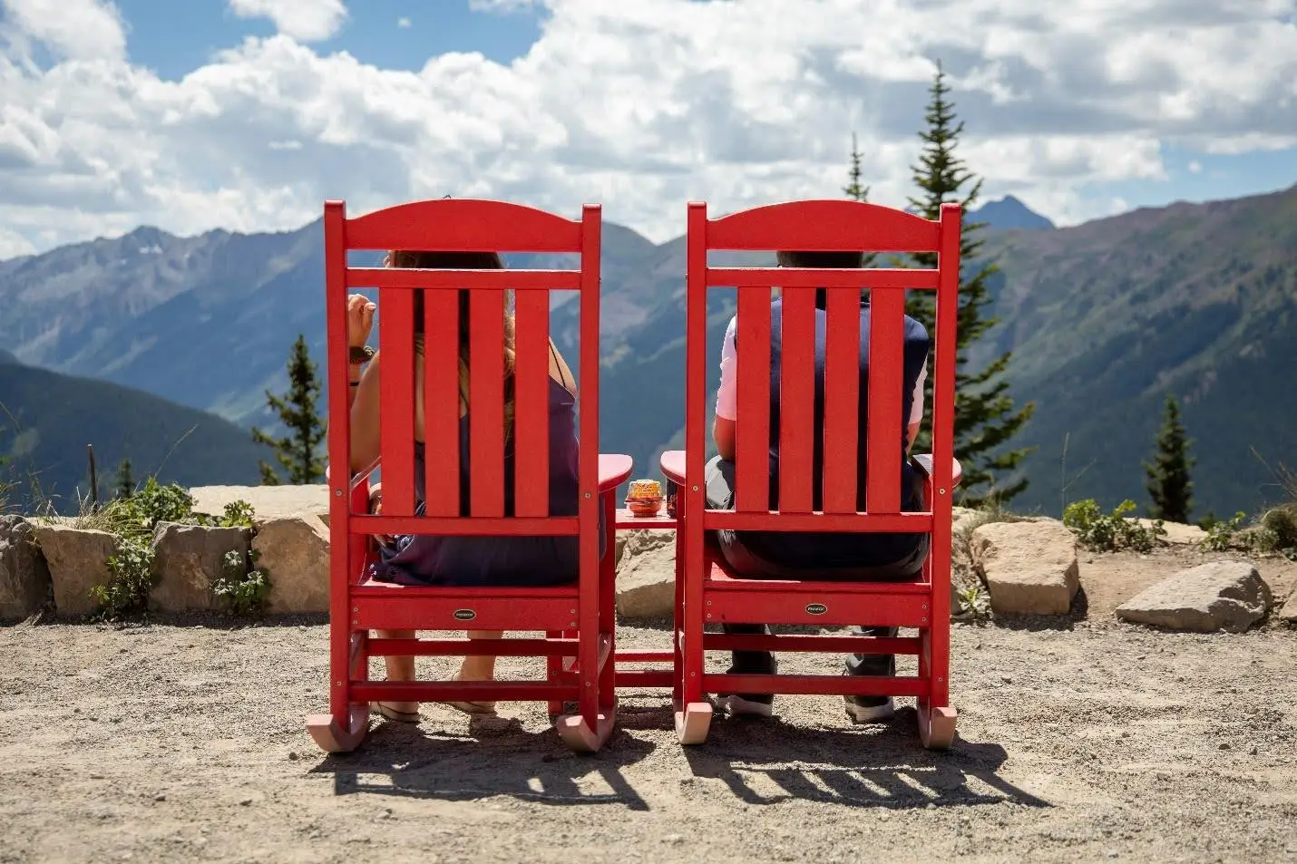 Red Polywood rocking chairs with scenic mountain views.